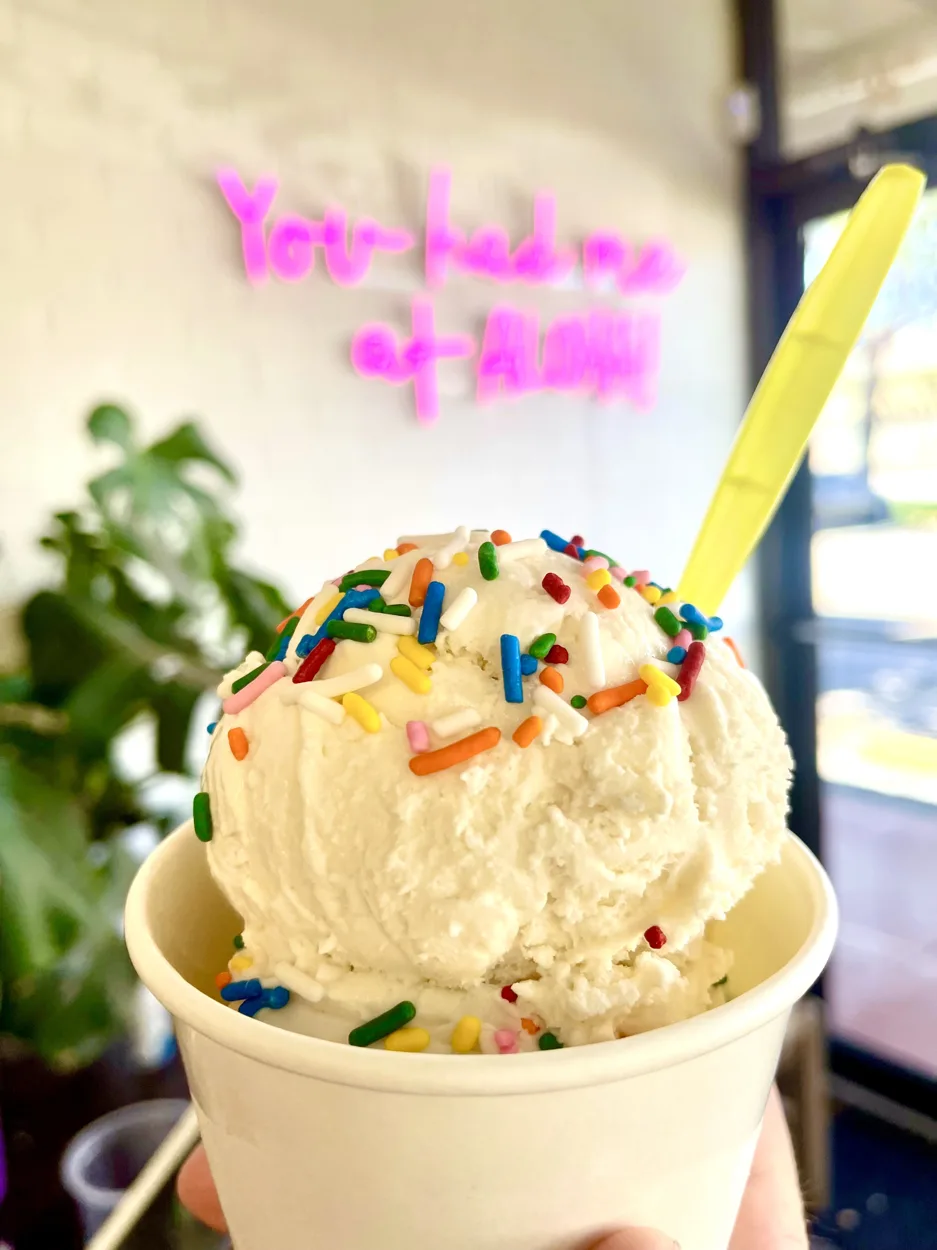 A double scoop of Birthday Cake ice cream with rainbow sprinkles in a cup