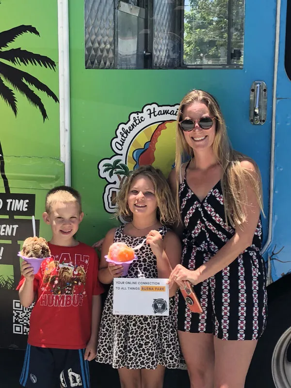 Ice cream catering in South Florida: a mom and two kids holding shave ice and ice cream at an outdoor event